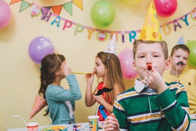 boy-blowing-noisemaker-birthday-party_23-2147773173
